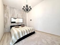 Elegancka sypialnia z kryształowym żyrandolem i tapetowaną ścianą akcentową — Łódź