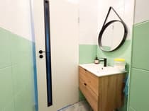 Łazienka z zielonymi płytkami, dębową szafką i kabiną prysznicową