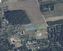 Widok na okolicę działki z zieloną łąką i zabudowaniami w tle