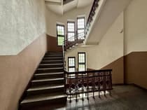 Reprezentacyjna klatka schodowa z kutą balustradą i przeszklonymi oknami w kamienicy