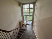 Klatka schodowa z dużym oknem i widokiem na zieleń — budynek Łódź-Zarzew 46 m²