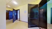 Korytarz z ciemnymi drewnianymi drzwiami i żółtymi ścianami w kamienicy na Bałutach
