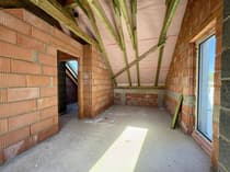 Pomieszczenie na piętrze pod skosem dachu – drewniana więźba, ceglane ściany, dom Mauryców