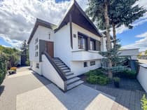 Salon z czarną skórzaną sofą i parkietem w jodełkę — dom na sprzedaż Łask