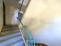 Dolna kondygnacja klatki schodowej z turkusową balustradą i skrzynkami na listy
