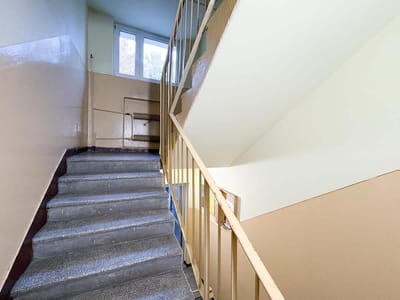 Widok schodów w budynku mieszkalnym z metalowym poręczem i jasnymi ścianami. mieszkanie na sprzedaż Łódź Retkinia - Florecistów