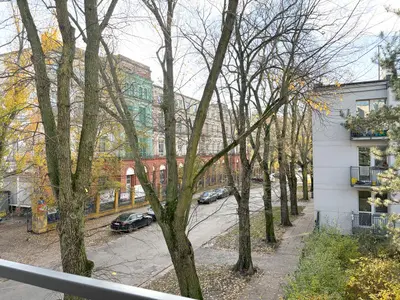 Widok z balkonu na aleję z jesiennymi drzewami i kamienicami – Śródmieście Łódź