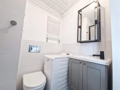 Kompaktowa łazienka z pralką, szarą szafką z lustrem, suszarką sufitową — Zduńska Wola