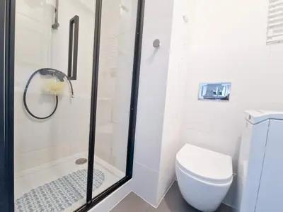 Łazienka z przeszkloną kabiną prysznicową z czarną armaturą i podwieszaną toaletą