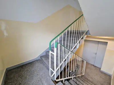 Klatka schodowa z szarymi stopniami i białymi balustradami z zieloną poręczą — Zduńska Wola