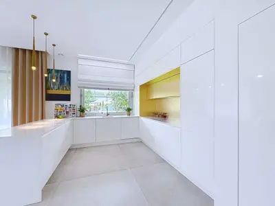 Kuchnia z dużą wyspą, złotą wnęką zabudowaną i złotymi lampami