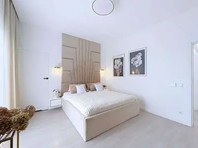 Sypialnia główna z tapicerowanym zagłówkiem i kinkietami złotymi — dom Ostrów