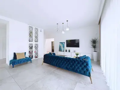 Salon z niebieską sofą Chesterfield, biblioteczką i telewizorem