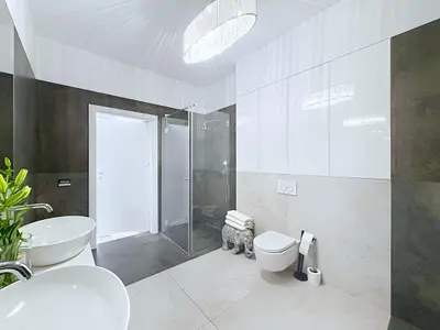 Druga łazienka z prysznicem, umywalkami i ceramiką podwieszaną