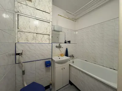 Łazienka z wanną, umywalką i białymi kaflami w mieszkaniu na sprzedaż Łódź-Teofilów