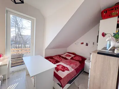 Pokój na poddaszu z łóżkiem jednoosobowym i oknem balkonowym