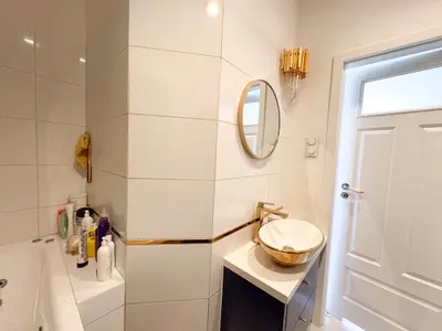 Łazienka ze złotymi akcesoriami, wanną i naczyniową umywalką