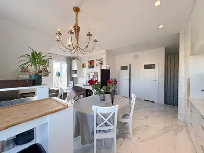 Salon z jadalnią w otwartym układzie i żyrandolem w domu w Łasku