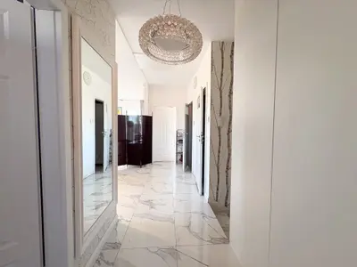 Przestronny korytarz z marmurową posadzką i kryształowym żyrandolem w Łasku