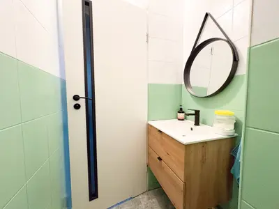 Łazienka z zielonymi płytkami, dębową szafką i kabiną prysznicową