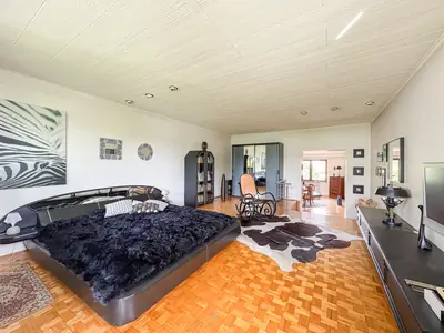 Sypialnia z czarnym łóżkiem dwuosobowym i parkietem w jodełkę