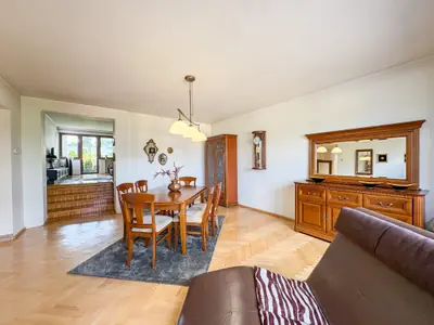 Jadalnia z drewnianą komodą i lustrem, widok na salon