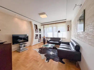 Salon z czarną skórzaną sofą i parkietem w jodełkę — dom na sprzedaż Łask