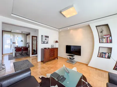 Salon z widokiem na jadalnię, parkiet drewniany i wnęka biblioteczna w łuku