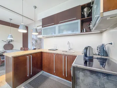 Kuchnia z płytą indukcyjną i ciemnymi szafkami, okap i szklane fronty