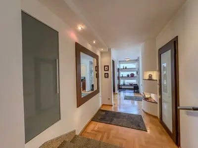 Jasny korytarz z lustrem w drewnianej ramie i parkietem w jodełkę