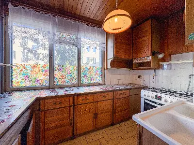 Kuchnia z drewnianymi szafkami, gazową kuchnią i oknem z roletą w Łodzi