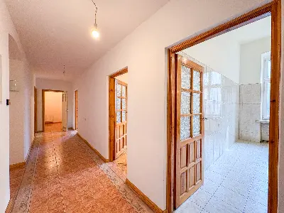 Długi korytarz z boazerią i drzwiami do łazienki w kamienicy w centrum Łodzi