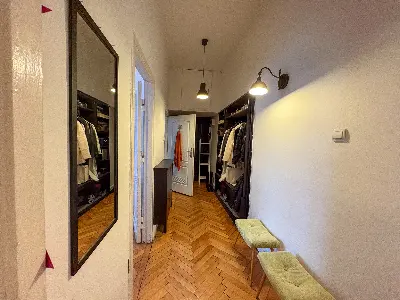 Przedpokój z otwartą garderobą, lustrem i ławeczką w kamienicy w Łodzi