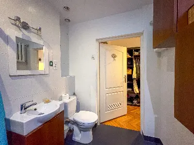 Łazienka z umywalką i toaletą na tle garderobą w kamienicy na Polesiu