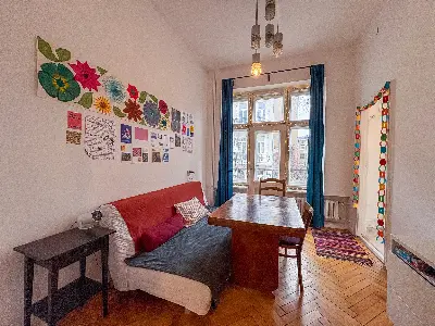 Salon z sofą, stołem i dużym oknem z zasłonami w kamienicy na Polesiu