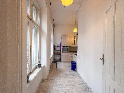 Korytarz z widokiem na kuchnię i wysokimi oknami w mieszkaniu na Polesiu