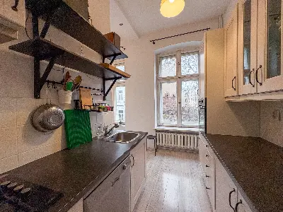 Kuchnia z ciemnym blatem i oknem na podwórze w kamienicy na Polesiu w Łodzi