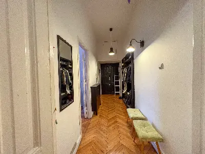 Przedpokój z ciemnymi drzwiami wejściowymi i parkietem w jodełkę