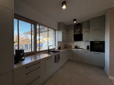 Kuchnia w kolorze szałwii z drewnianym blatem i dużym oknem