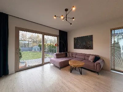 Salon z narożną sofą i dużymi przeszklonymi drzwiami tarasowymi