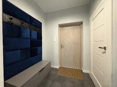 Przedsionek wejściowy z granatową tapicerowaną ścianą i wieszakami