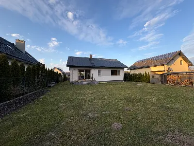 Dom parterowy 111m² widziany od strony ogrodu, biała elewacja z panelami PV — Księstwo, łódzkie