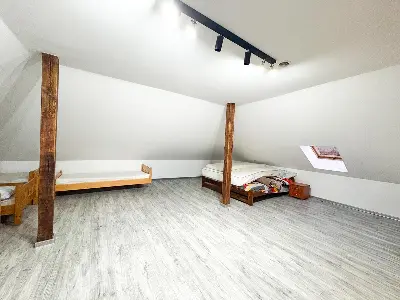 Poddasze z drewnianymi belkami i dwoma łóżkami, okno dachowe