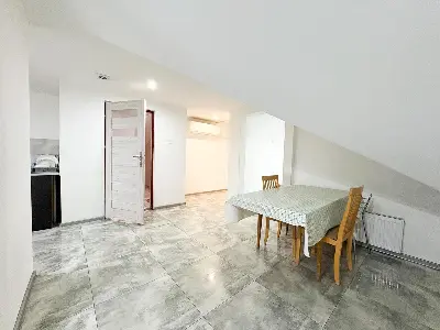 Aneks kuchenny na poddaszu ze stołem i krzesłami, skośne ściany