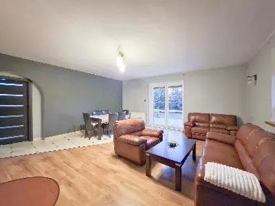 Salon z jadalnią, skórzana sofa i fotele, łukowe przejście w domu w Swędowie