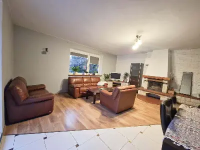 Przestronny salon z kominkiem kamiennym i skórzanymi kanapami — dom 130m² Swędów