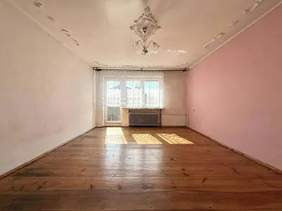 Jasny pokój z drewnianą podłogą, różową ścianą i ozdobnym medalionikiem na suficie