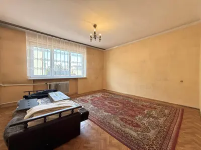 Duży pokój z parkietem w jodełkę, żółtymi ścianami i czerwonym dywanem