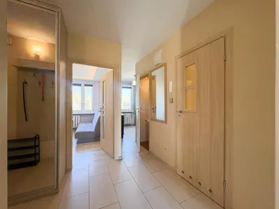 Jasny korytarz z drzwiami do pokojów i szafą — wnętrze mieszkania na Bałutach w Łodzi