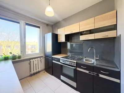 Kuchnia z czarno-drewnianą zabudową, kuchenką gazową i oknem — Łódź-Bałuty